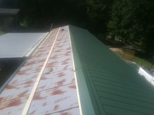 Old rusted panels beside newly installed green metal roofing — Wind Damage Roof Repair by Roofing Brothers in West Union